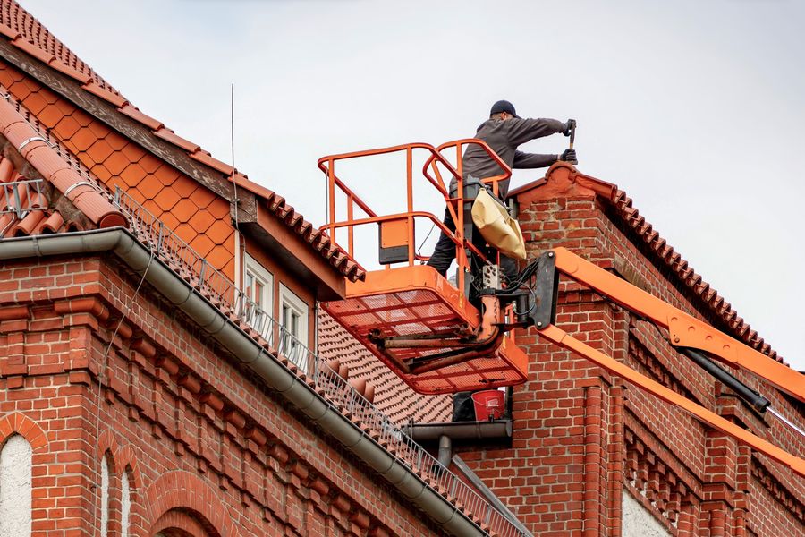 Roofer on a cherry picker servicing a brick building