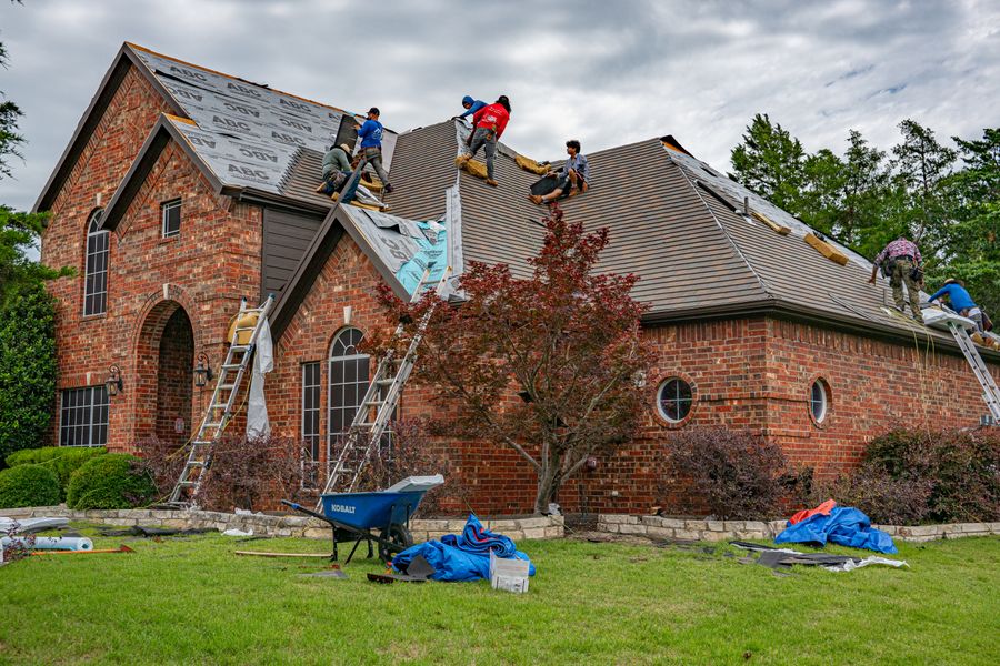 Roofers working on a brick home’s shingles
