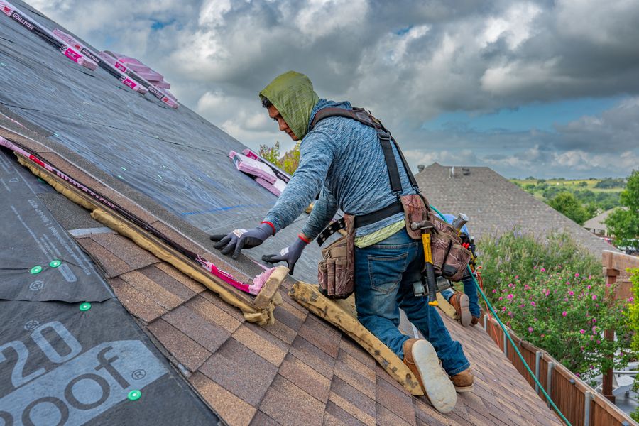 Roofers re-covering a house roof in bright sun